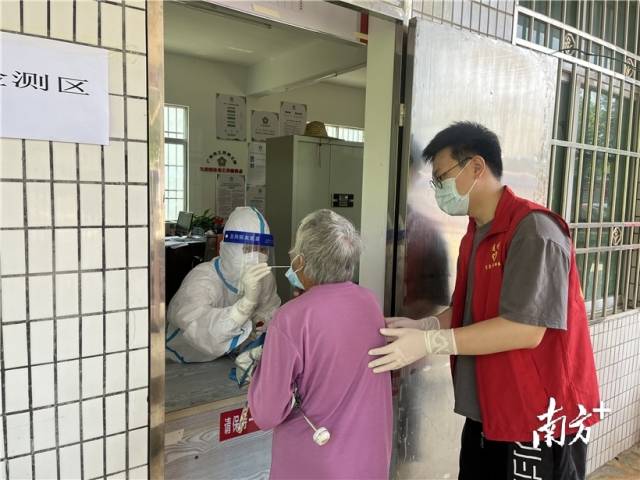 現(xiàn)場志愿者幫助行動不便群眾接受核酸檢測。